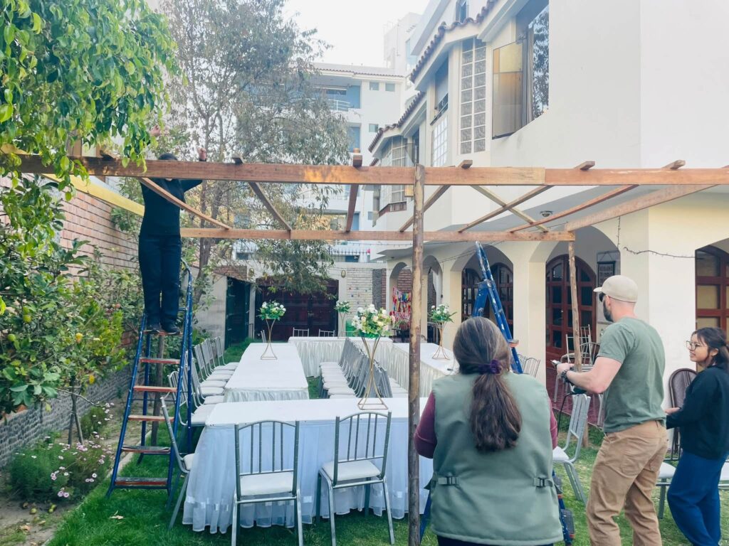 Raising the sukkah beams over the tables in the garden