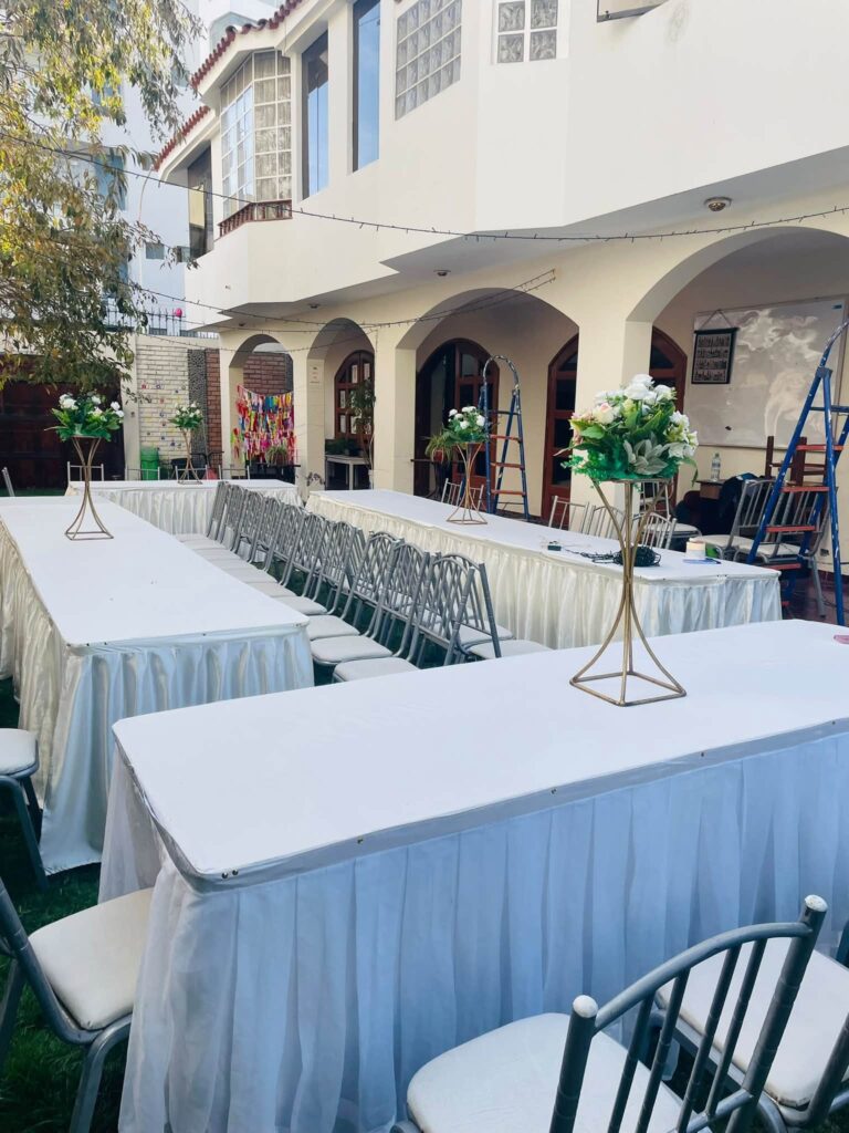 White tables and flowers set for the Sukkot feast under the arches of the home