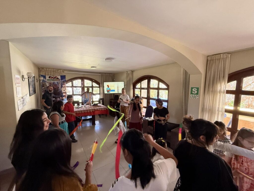 Girls waving coloured ribbons in the living room as the ribbon dance begins