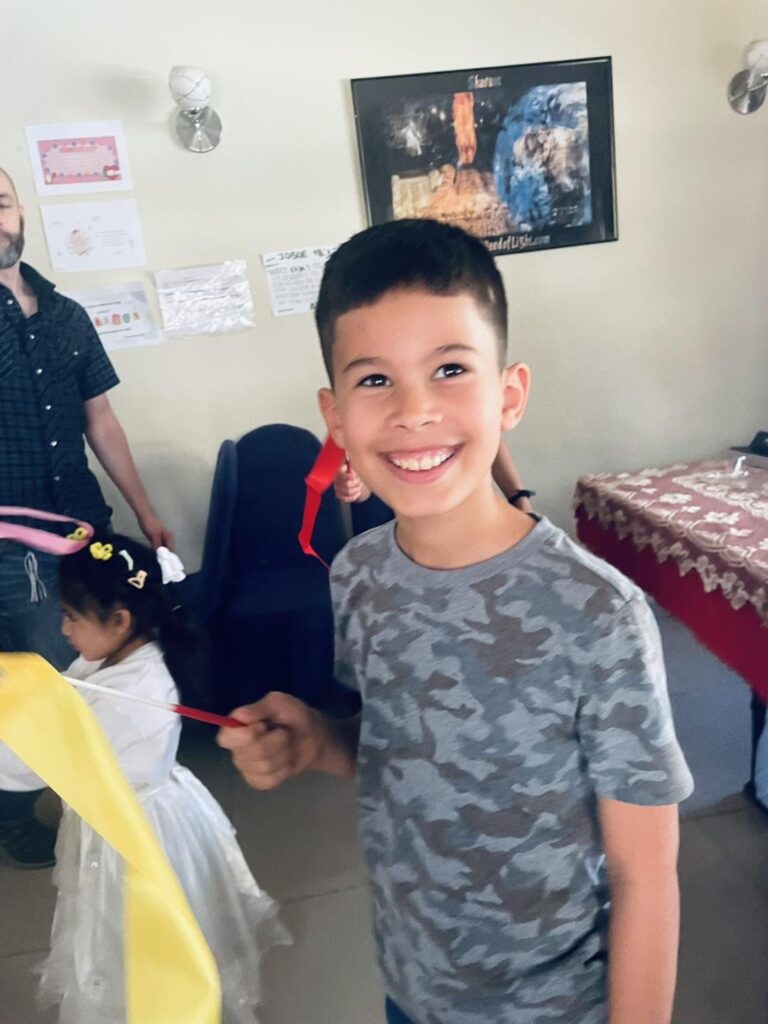 A smiling boy holding a red ribbon during the dance